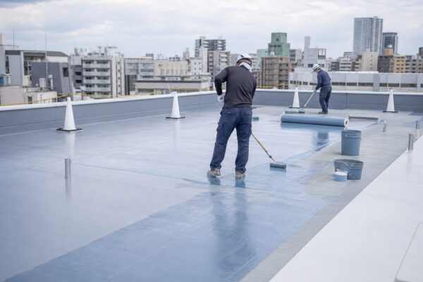 屋上で防水工事を行う現場